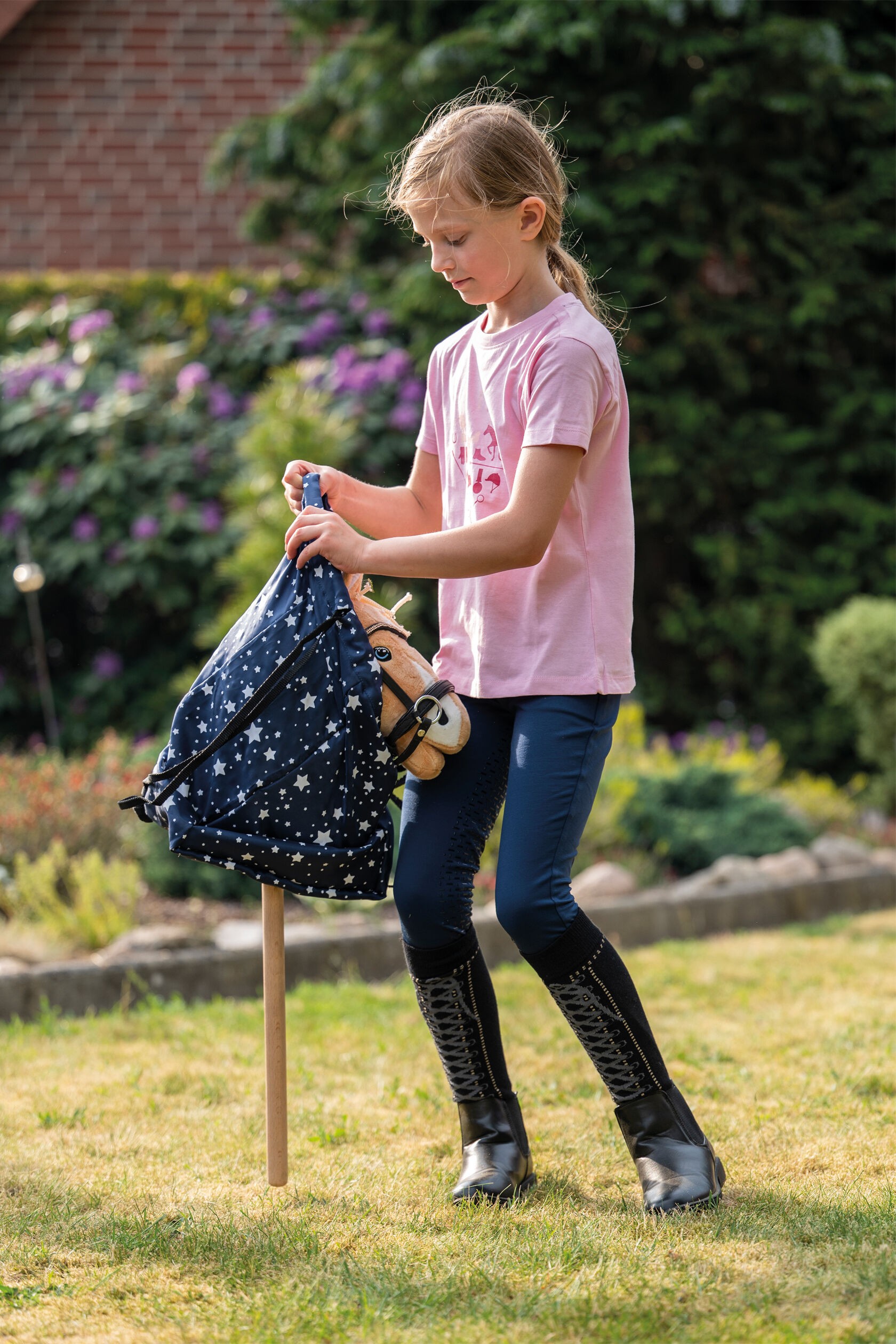 Mädchen verpackt Hobby Horse in HKM Transportbeutel und verschließt ihn